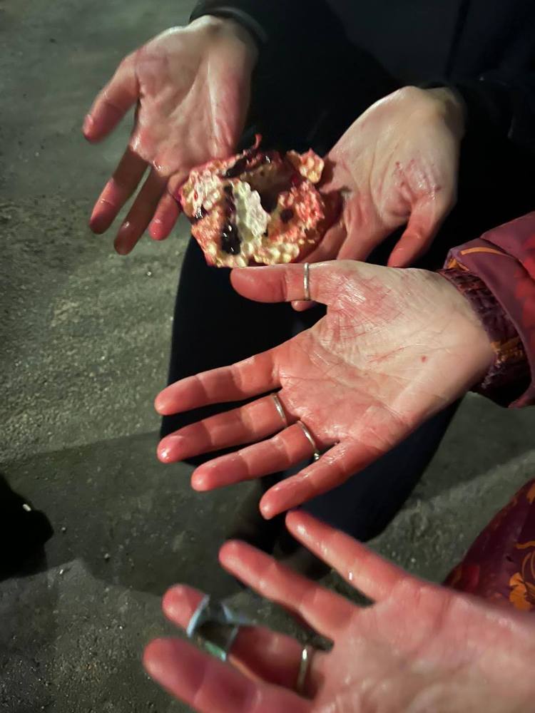 Hands stained red by a broken pomegranate
